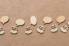 Wooden Owl Shapes With Wooden Speech Bubbles On Plain Brown Paper