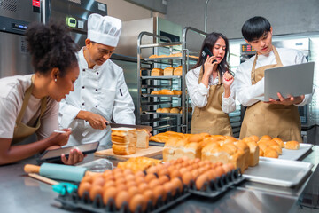 Wall Mural - Cooking  course , senior Asian male chef in cook uniform teaches young asian and african american people cooking class students to prepare, mix ingredients for pastry foods, in restaurant stainless 