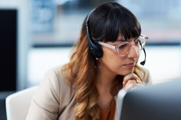 Poster - Always trying to help. Cropped shot of an attractive young businesswoman sitting and using a headset in her office during the day.
