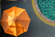 An Open Parasol By The Swimming Pool At Sunset.