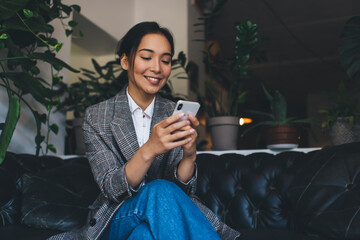 Fototapete - Happy Asian female blogger connecting to 4g wireless on cellphone for sending text sms, cheerful hipster girl making online booking via mobile application on smartphone - enjoying web communication
