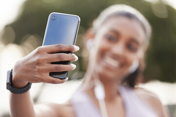 Sticker - Her phone is filled with photos of her progress. Closeup shot of a sporty young woman wearing earphones and taking selfies while exercising outdoors.