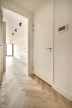 A Narrow Corridor With Parquet Floor Leading Inside A Cozy House In White