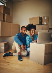 Poster - We dont have much yet but we will. Shot of a cheerful young couple browsing on a laptop together while being surrounded by cardboard boxes inside at home.