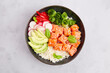 Poke bowl with salmon tuna, rice, avocado, cucumber, radish, pepper, sesame seeds on grey background. Close-up. Hawaiian diet food with fish, pokebowl. Top view. 