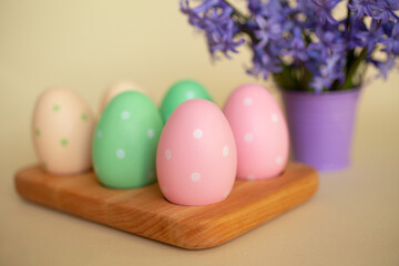  Pastel Easter eggs in the wooden tray.Violet flowers on background.