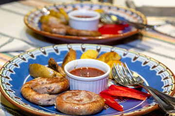 Wall Mural - Fried sausages with potatoes and tomato sauce are on a plate