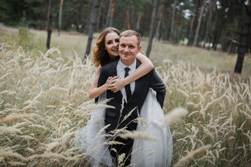 Wedding couple in the park. An elegant bride of European appearance and a groom in a black suit.