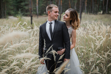 Wedding couple in the park. An elegant bride of European appearance and a groom in a black suit.