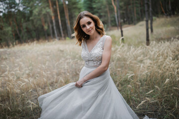 Wall Mural - A beautiful, satisfied bride in a pine forest poses.