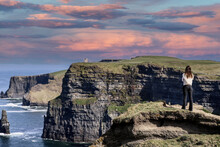 A Women Admires The Cliffs Of Moher Views, Sea Cliffs Located At The Southwestern Edge Of The Burren Region In County Clare, Ireland