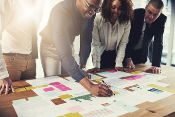 Poster - Making a note. Cropped shot of a group of businesspeople going over paperwork during a meeting in their office.