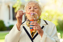 Shes On A Playdate With Her Inner Child. Shot Of A Fun-loving Senior Woman Blowing Bubbles Outside On A Sunny Day.