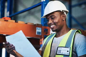 Canvas Print - Time to put everything in its place. Shot of a handsome young contractor standing in the warehouse and reading paperwork.