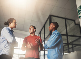 Wall Mural - Sharing his thoughts with the team. Shot of three colleagues having a discussion in an office.