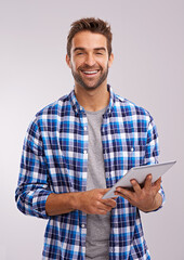 Poster - Checking in Studio. Studio shot of a handsome young man using a digital tablet against a gray background.