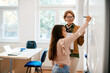 © Drazen - Mature teacher assists schoolgirl in writing assignment on smartboard in the classroom.
