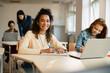 © Drazen - Happy black student takes notes while using laptop with her classmate during a class at high school.
