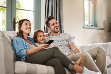 Wall Mural - Better than the movie theatre. Shot of a happy young family relaxing on the sofa and watching tv together at home.