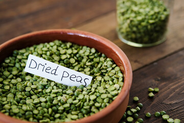 Dry green peas in a bowl. Split green peas. Peas on a wooden background. Side view. Lettering green dry peas.