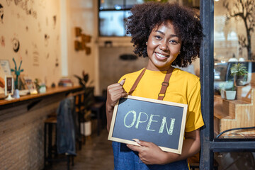 Young Female manager in restaurant with digital tablet or notebookWoman coffee shop owner with face mask hold open sign .Small business concept.