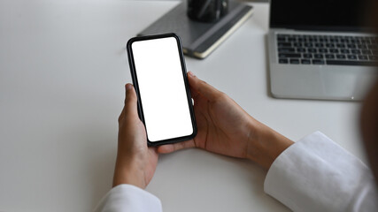 Poster - Top view close up of hands leaning to the table in the office holding a smartphone with a blank  white screen, for business and technology concept.