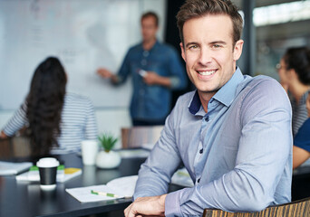 Poster - Success starts in the boardroom. Portrait of an office worker sitting in a meeting with his colleagues in the background.