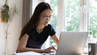 © fizkes - Busy student girl in glasses studying use laptop, prepare for university exams looks focused, serious concentrated woman working sit at table staring at computer screen. Modern tech, e-learn concept