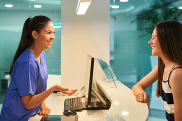 Aufkleber - Are you here for a checkup. Shot of a young nurse assisting a patient at the reception desk.