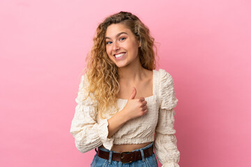 Wall Mural - Young blonde woman isolated on pink background giving a thumbs up gesture