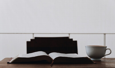 The Bible is placed on a wooden table with coffee in a quiet white room. Ready to learn and study the Bible . The concept of studying the Bible . Faith. Trust in God.