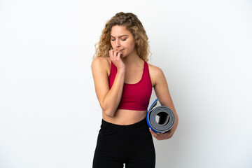 Wall Mural - Young sport blonde woman going to yoga classes while holding a mat isolated on white background having doubts