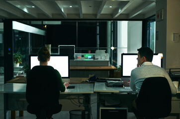 Leinwandbilder - Making success happen at all hours of the day and night. Rearview shot of two businesspeople working on computers in an office at night.