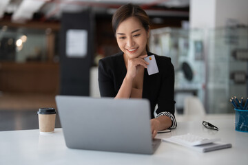 Asian girl making online payment using laptop and credit card for shopping at home