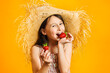 Little happy girl eat red ripe strawberries. Sweet juicy summer fruits. Yellow wall background in studio.