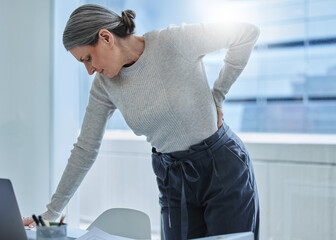 Wall Mural - Wheres the chiropractor when you need one. Shot of a mature businesswoman standing alone in the office and suffering from backache.