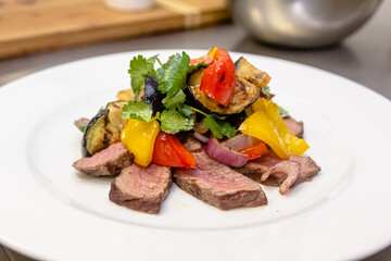 Wall Mural - A salad of baked eggplant, sweet pepper and beef with parsley is on a plate