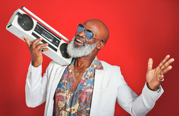 Poster - The kind of music you listen to says a lot about you. Studio shot of a senior man wearing vintage clothing while posing with a boombox against a red background.