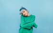 © bodnarphoto - Hipster girl with blue hair and in a green sweatshirt posing for the camera on a blue background