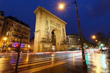 Porte Saint-Denis at rainy night . It is a Parisian monument located in the 10th arrondissement of Paris, France.