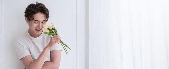 Portrait of young attractive asian man in white t shirt holding flowers as gift for mother or girlfriend on birthday. Happy anniversary present, Valentine's Day concept