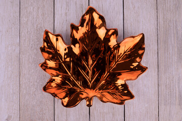 Wall Mural - Maple leaf shape plate disposed on a white wooden plank. Directly above.