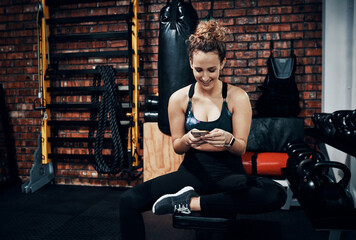 Poster - My medical aid rewards me every time I work out. Shot of a sporty young woman using a digital tablet while sitting in the gym.