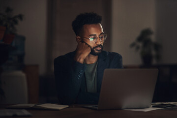 Poster - It might be time to re-evaluate why you work here. Shot of a young businessman looking worn out while using a laptop during a late night at work.