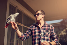 You Cant Tame The Truly Free. Shot Of A Young Man And An African Gray Perched On His Hand.