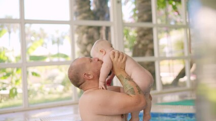 cute baby having swimming lesson with his mother and father. healthy family teaching their baby to s