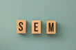 SEO - Search Engine Marketing letters made out of wood on the turquoise background