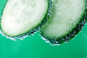 Cucumbers sliced with water bubbles on green background. Macro image, selective focus, abstract food background.