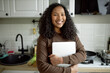 © Anatoliy Karlyuk - Lovely cute charismatic young teenage girl holding closed laptop in hands, smiling after finishing her home assignment, standing against kitchen background, feeling happy and carefree