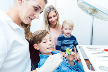 Poster - Family looking at boy choosing the colourful dental braces with female dentist doctor in clinic